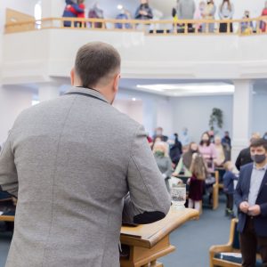 man in gray long sleeve shirt standing in front of brown wooden table